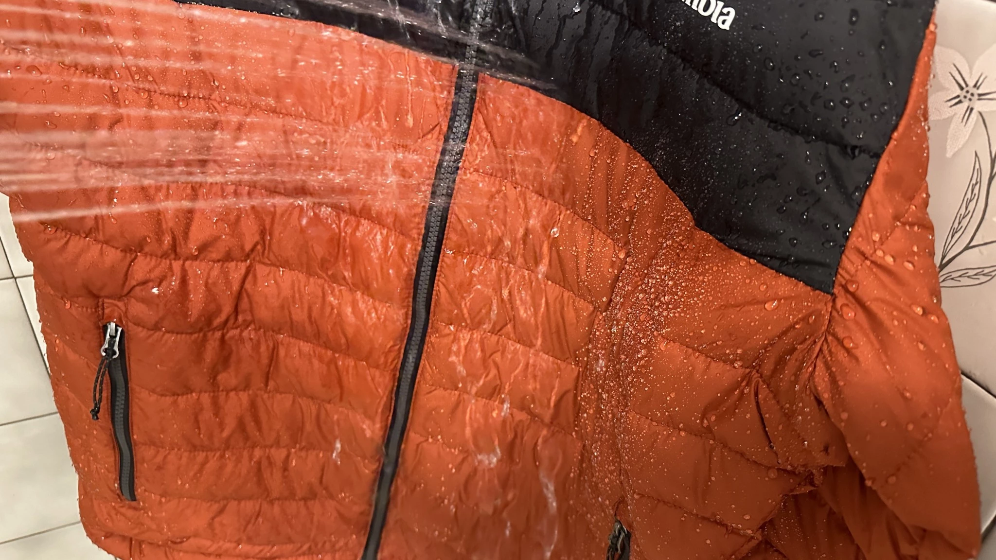 Water droplets being sprayed onto the shell of an insulated jacket to test its water resistance.