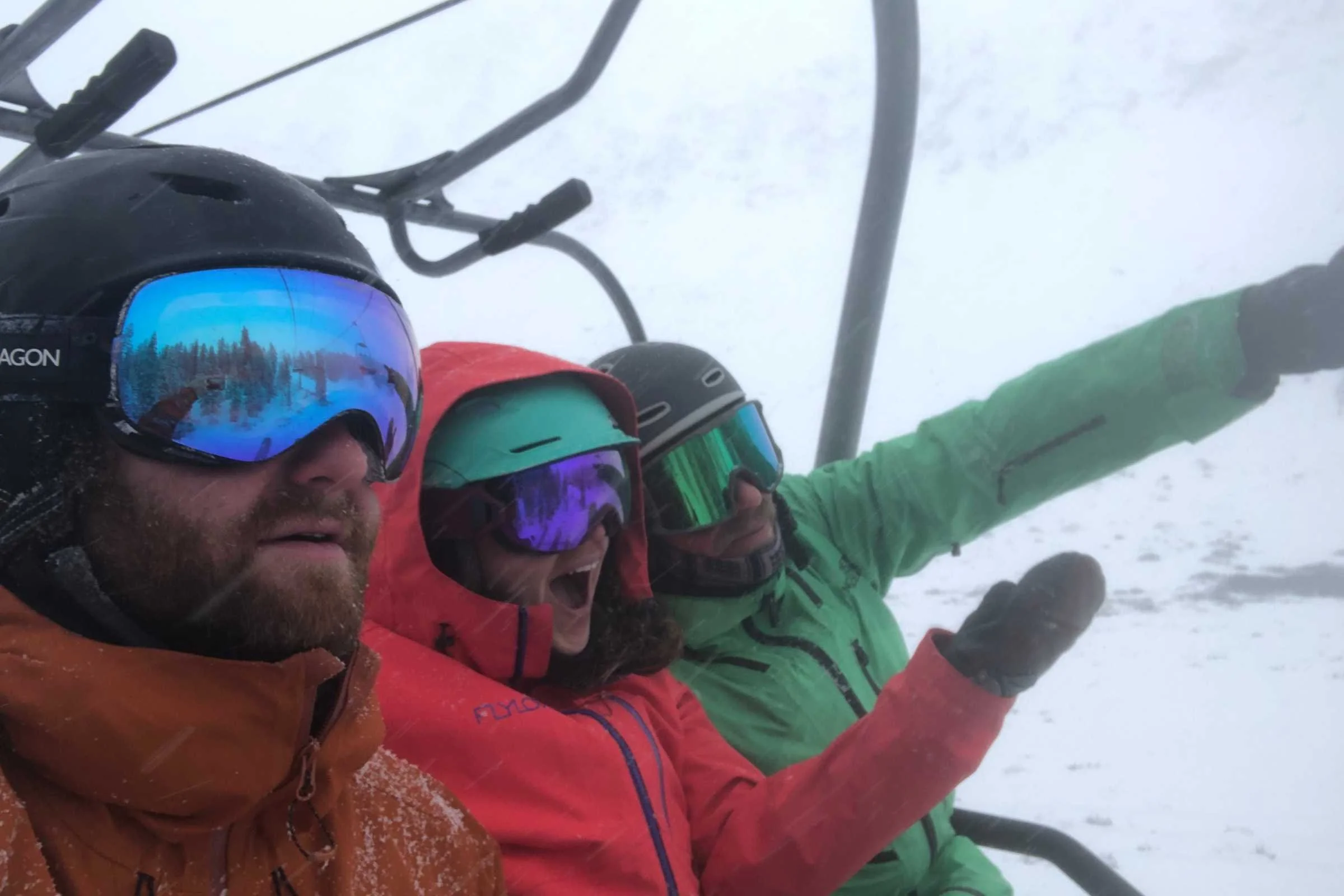A group of skiers wearing various technical jackets riding a chair lift.