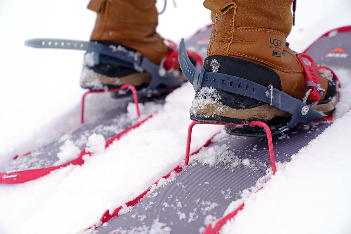 Close-up of a green snowshoe with the metal heel lift bar engaged.