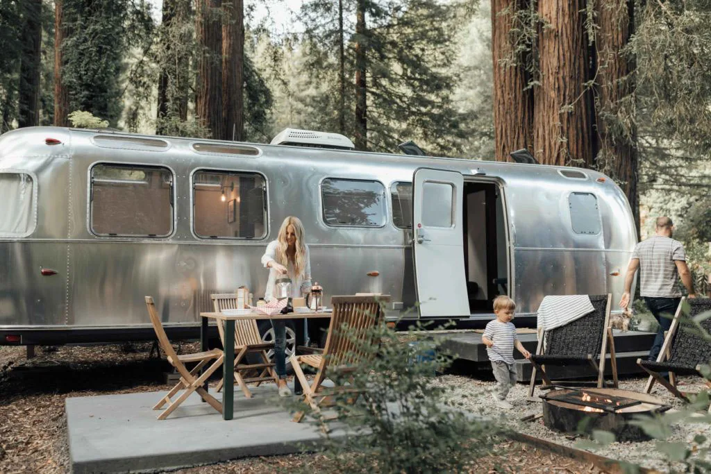 A modern silver Airstream trailer under a canopy of redwood trees at AutoCamp Russian River.