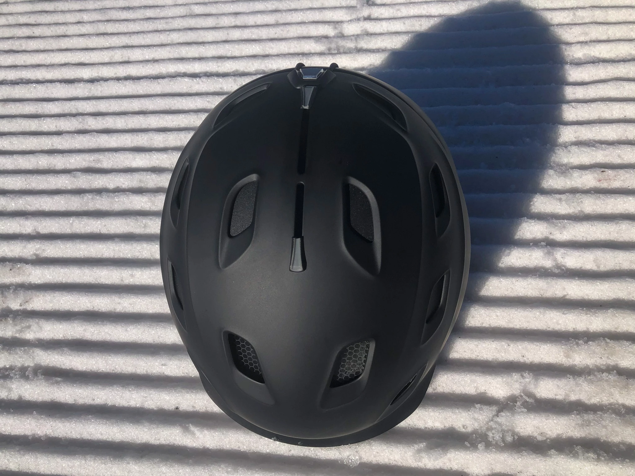 Detail shot of its adjustable vent sliders on the top of a grey ski helmet.