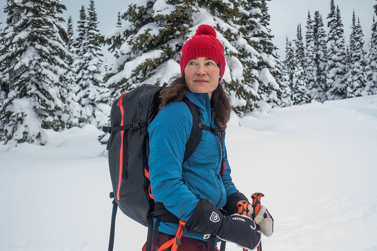 A woman standing in a snowy mountain landscape wearing a technical synthetic jacket.