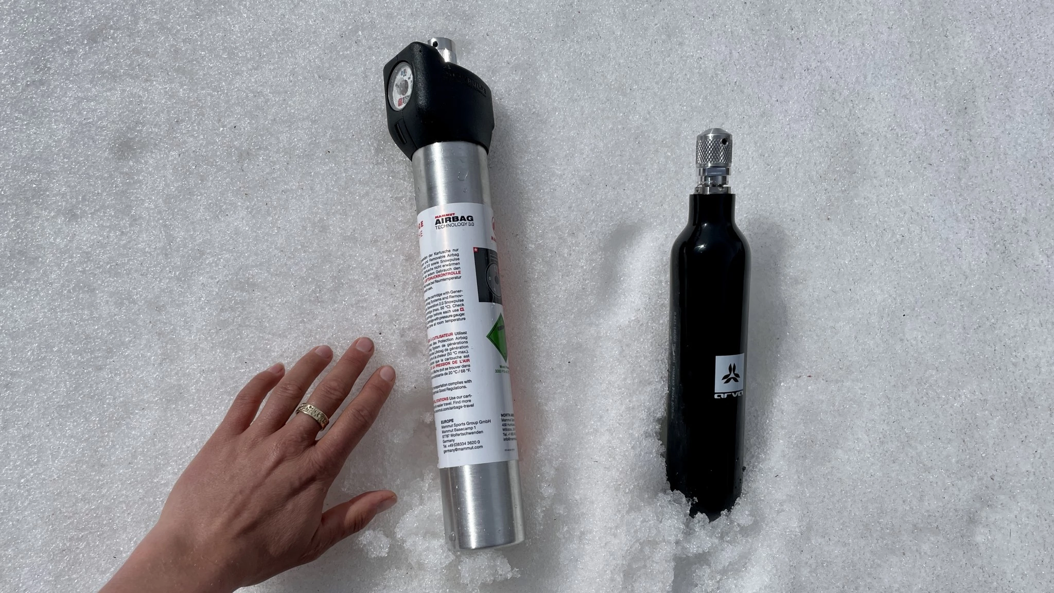 A comparison showing a black carbon compressed air canister and a silver aluminum canister.