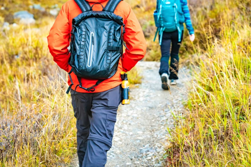 A group of hikers practicing holding bear spray canisters in an outdoor setting.