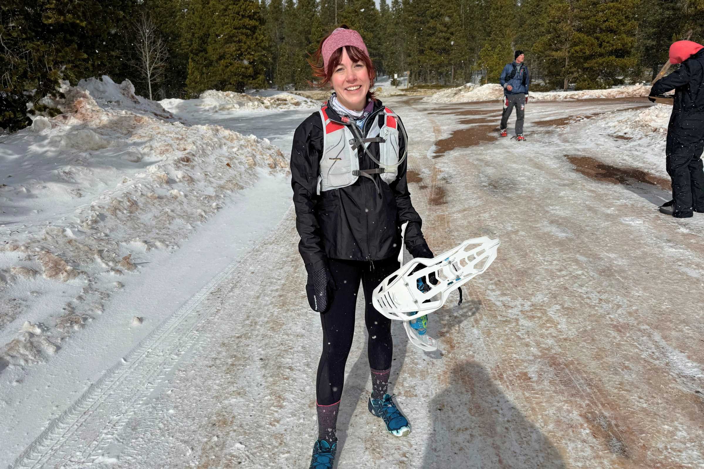 A runner fully geared in technical layers, a headband, and racing snowshoes.