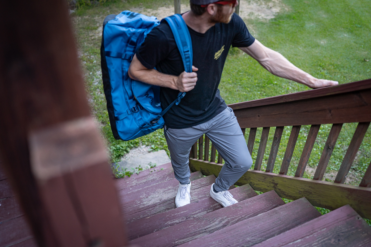 A person wearing Baleaf lightweight joggers while standing near travel gear.