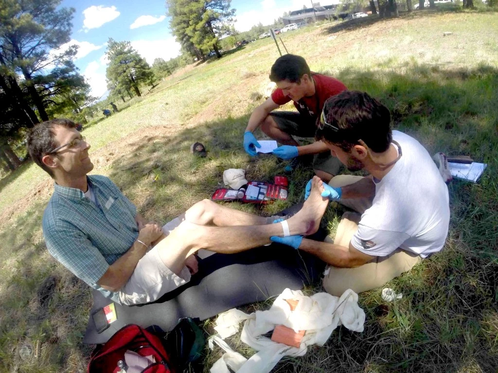 Students practicing ankle taping during a wilderness first responder training session.
