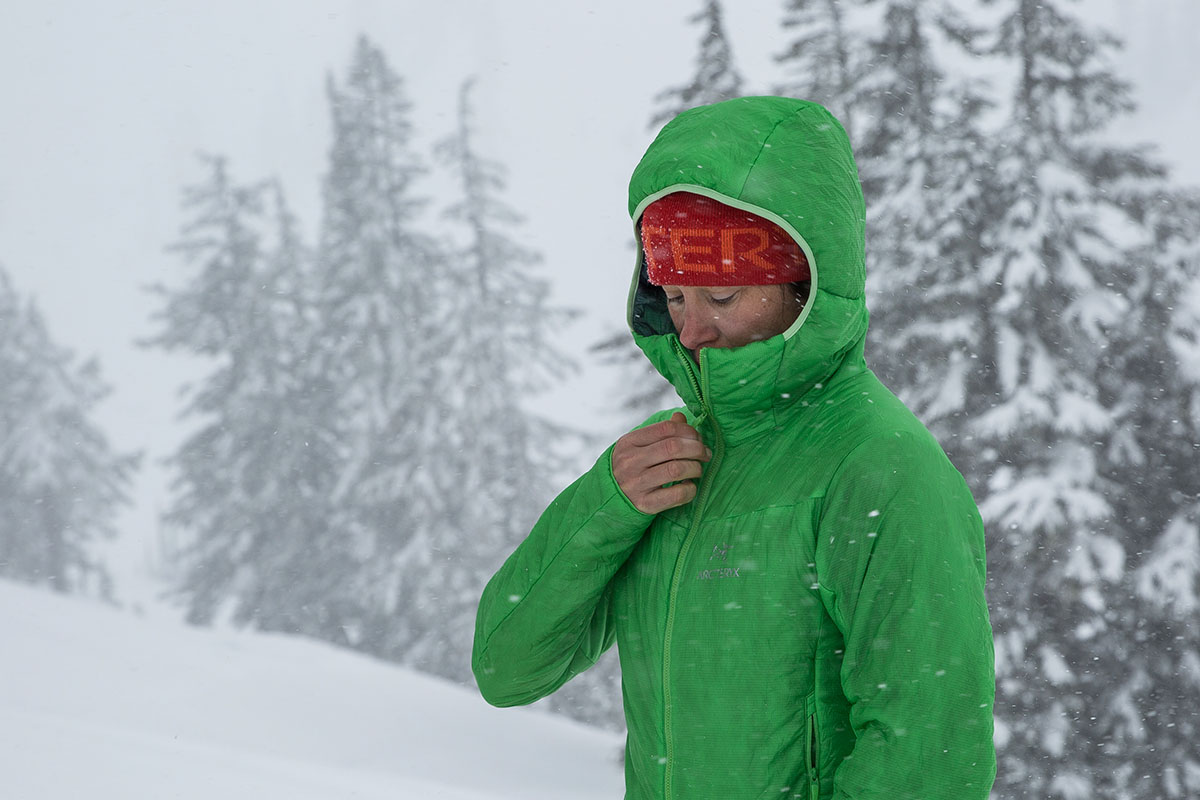 A woman zipping up a synthetic jacket in snowy conditions to show moisture resistance.
