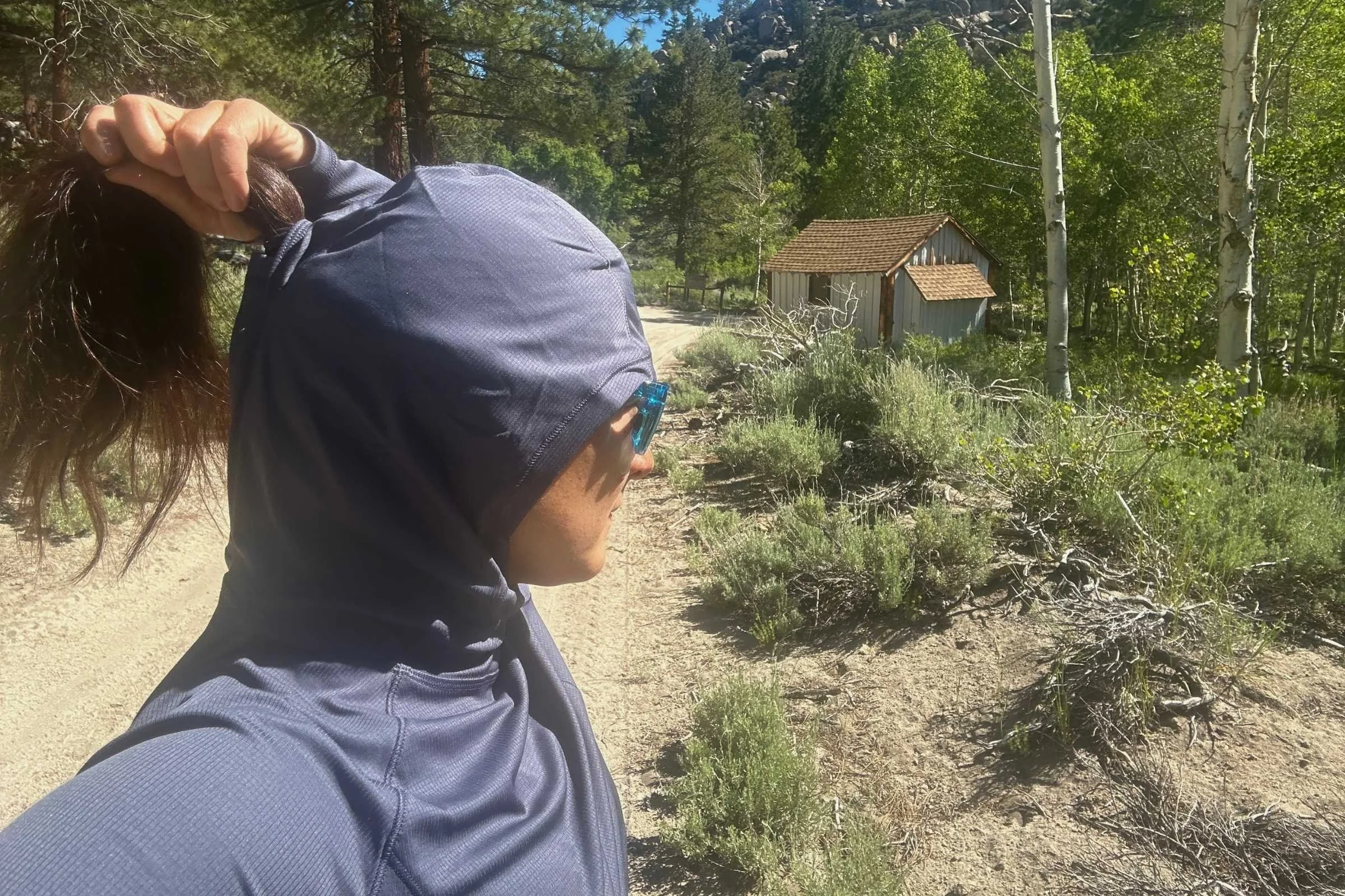 Rear view of the sun hoodie hood showing a ponytail pulled through the integrated port.