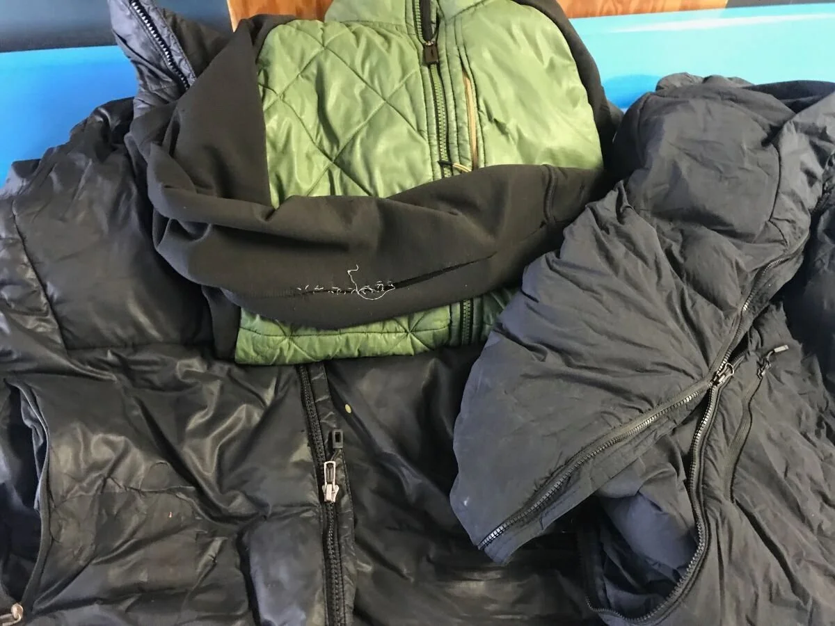 A collection of colorful outdoor jackets with various zipper configurations.