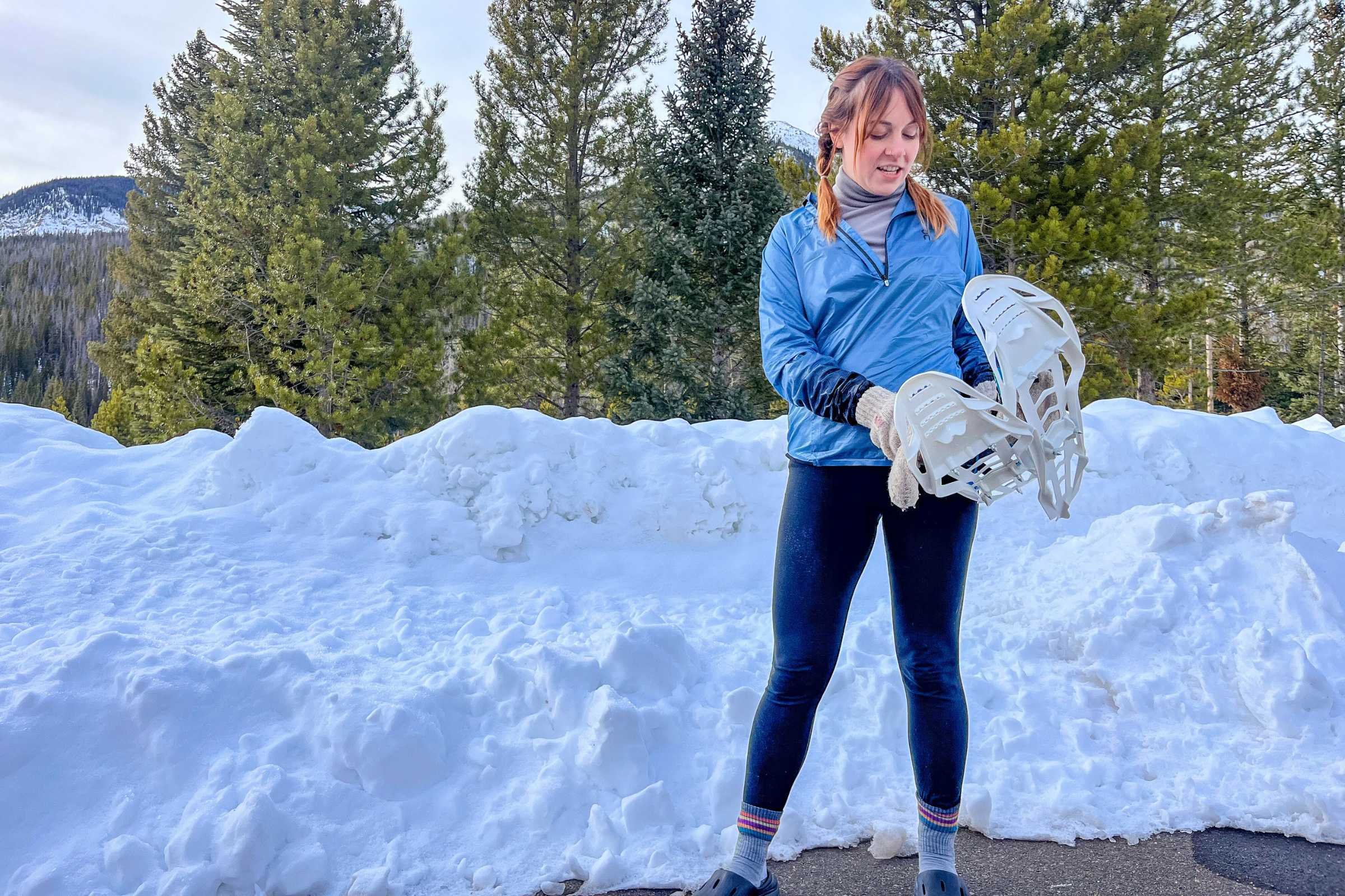 A runner on snowshoes navigating a groomed trail through a snowy forest.
