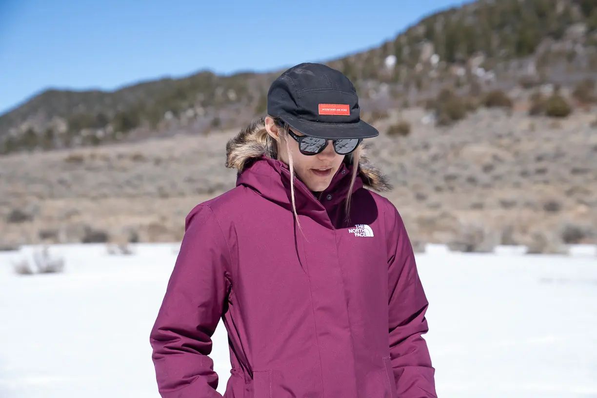 A woman wearing The North Face Arctic Parka with a hood and sunglasses