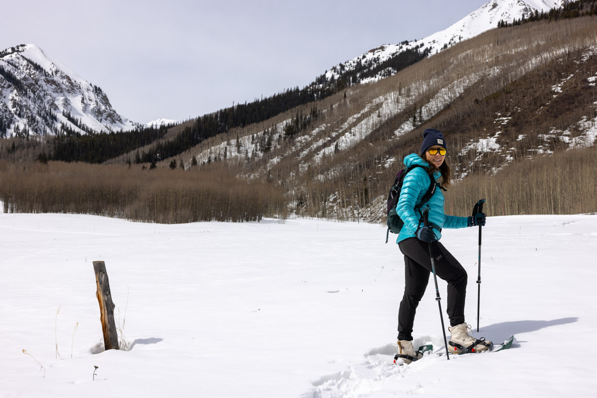 A woman smiling while snowshoeing through fresh powder snow.