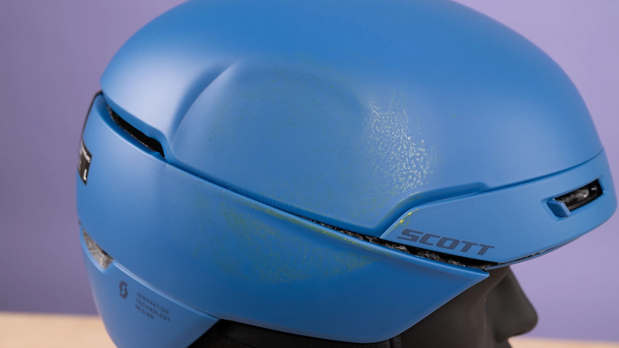 Close-up of a Scott Flow Pro helmet showing scuffs and damage after a laboratory drop test.