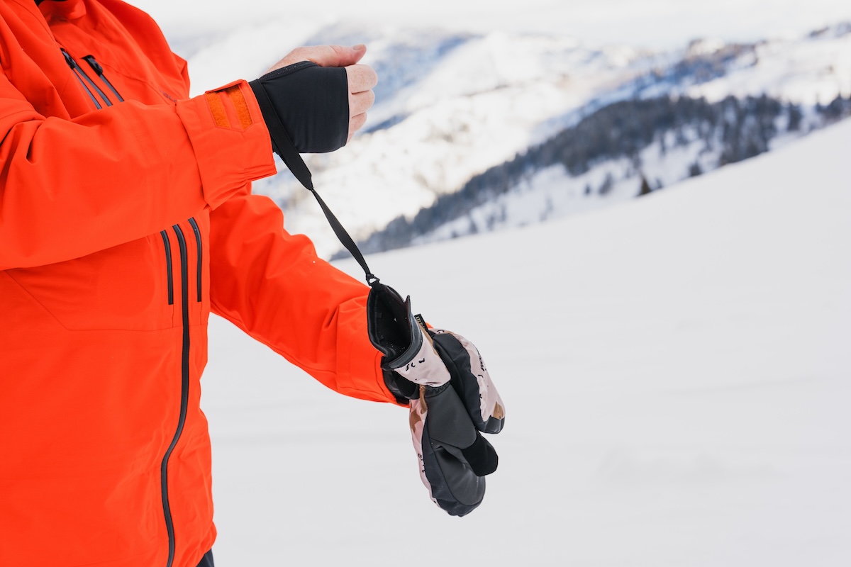 A close-up of a snowboarder wearing wrist leashes on their mittens.