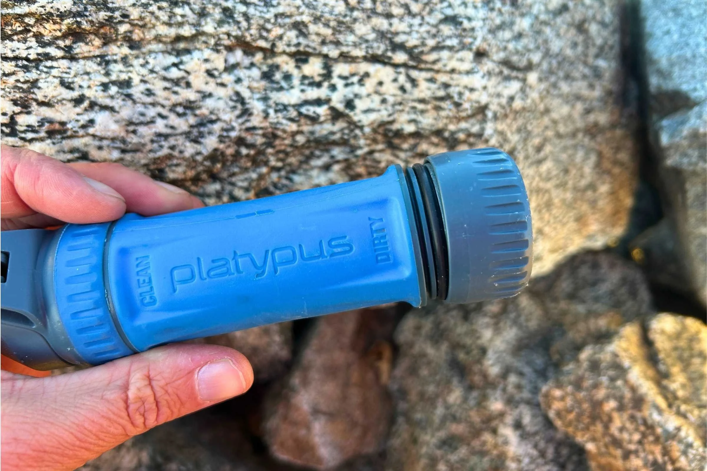 A close-up of a Platypus Quickdraw water filter with its protective end caps securely screwed on.