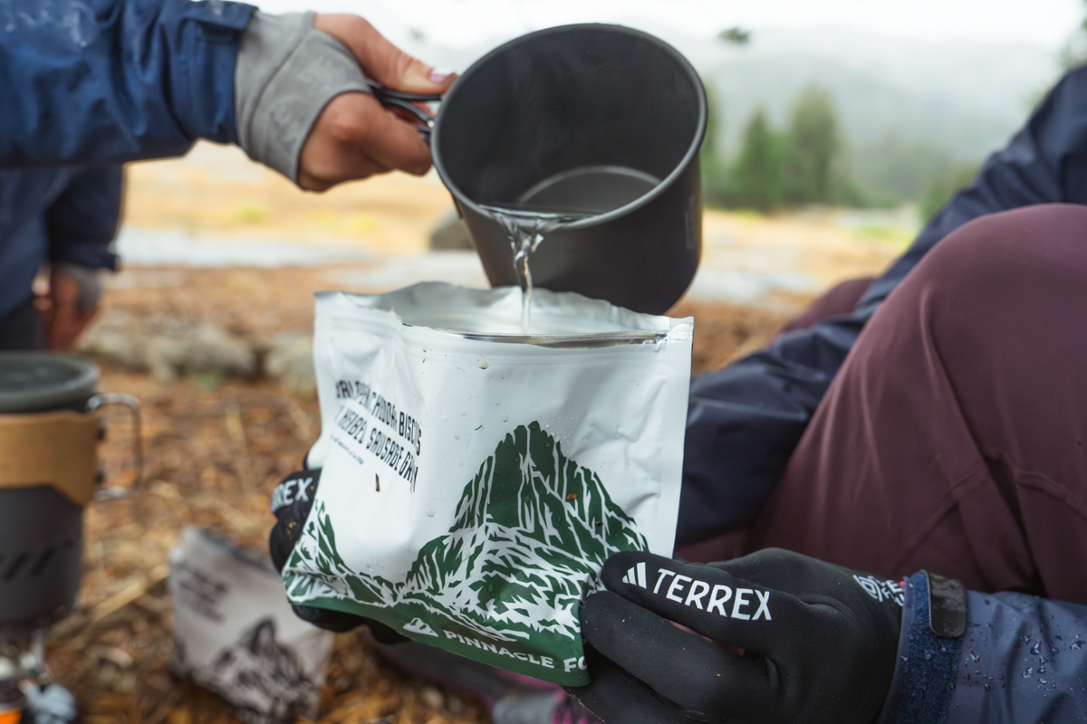 Hot water being poured from a jetboil-style stove into a Pinnacle Foods meal pouch.