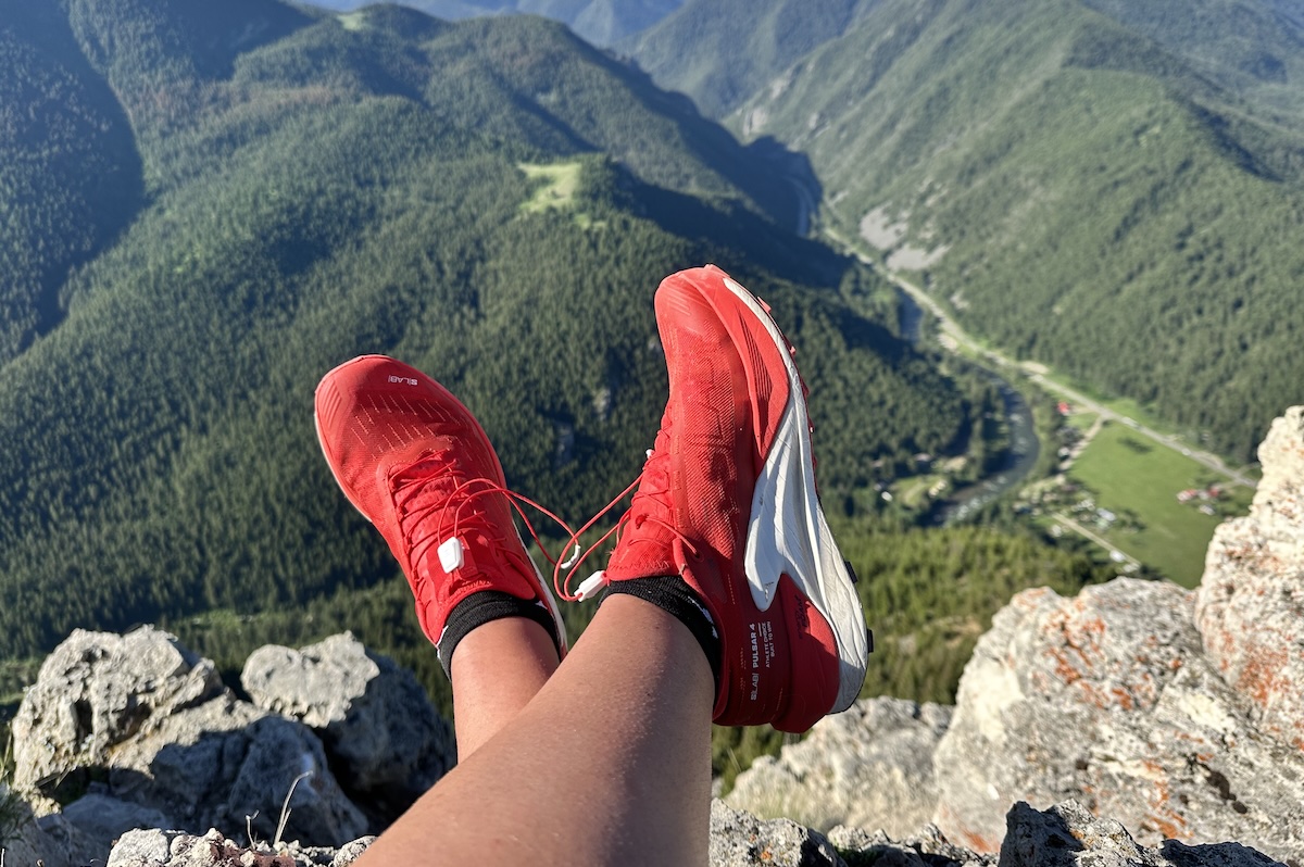 Close-up of red Salomon Pulsar 4 trail shoes resting on a rocky ledge.