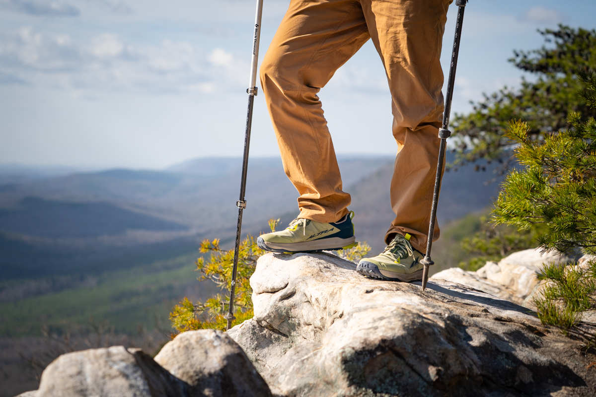 A hiker wearing Altra Lone Peak trail runners stands on a rocky outcropping.
