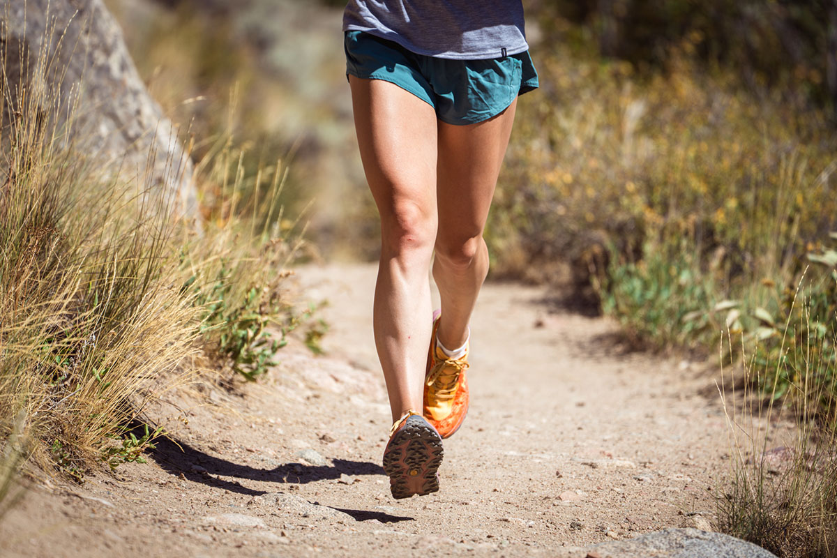 Waist-down action shot of a runner wearing Hoka Speedgoat 6 on a trail.