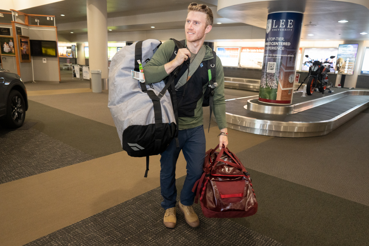 A man wearing Outdoor Research Ferrosi pants while walking through an airport terminal.