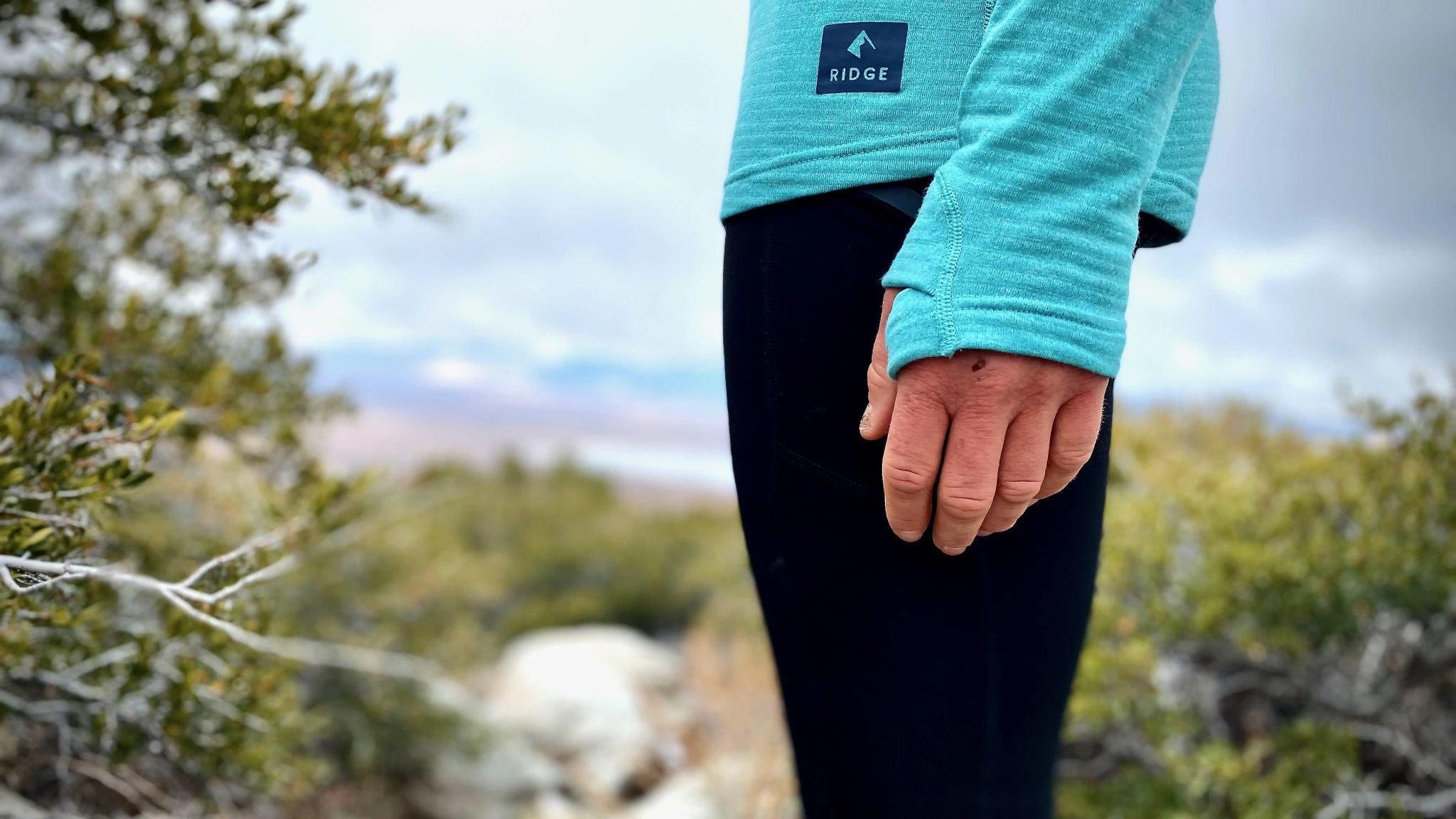 Close-up of a hand using a thumbloop on a purple base layer sleeve during a climb.