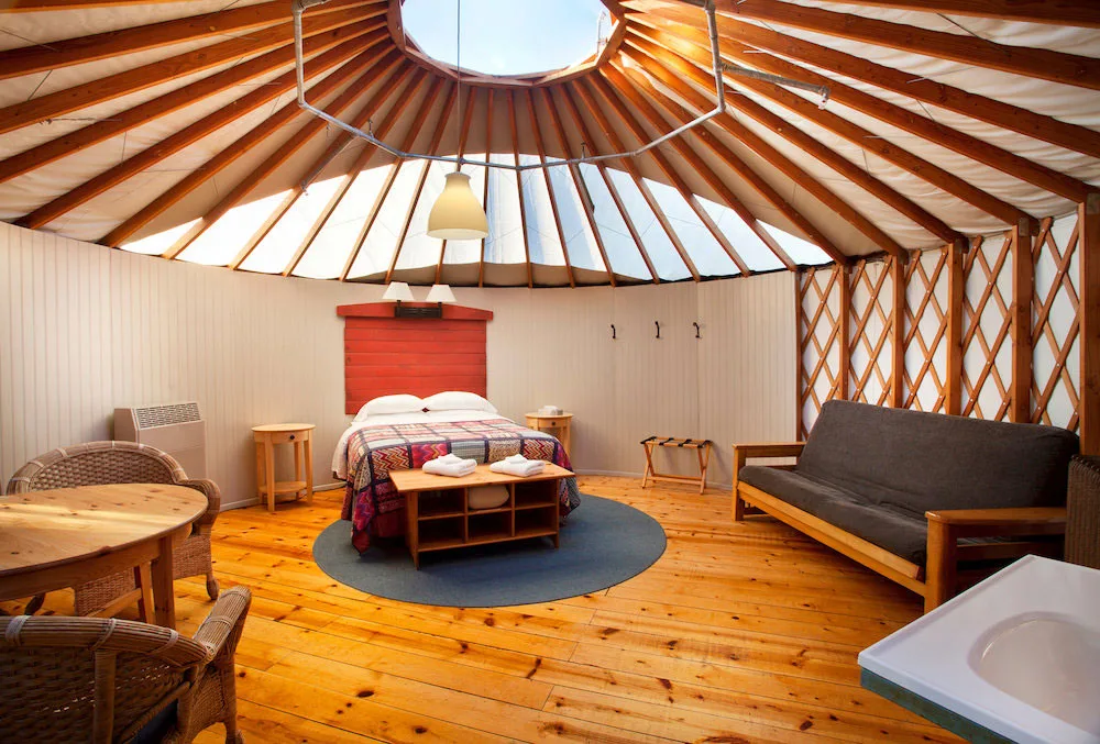 Warm, wooden interior of a luxury yurt at Treebones Resort with a large comfortable bed.
