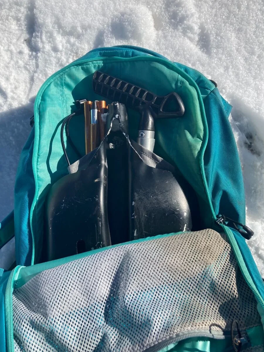 The internal storage compartment of an Osprey pack labeled for avalanche safety tools.