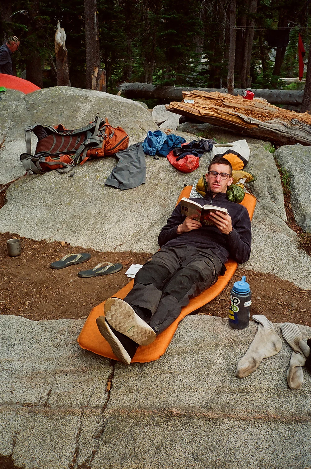 A hiker wearing technical pants traversing a rocky meadow on the Elkhorns trail.
