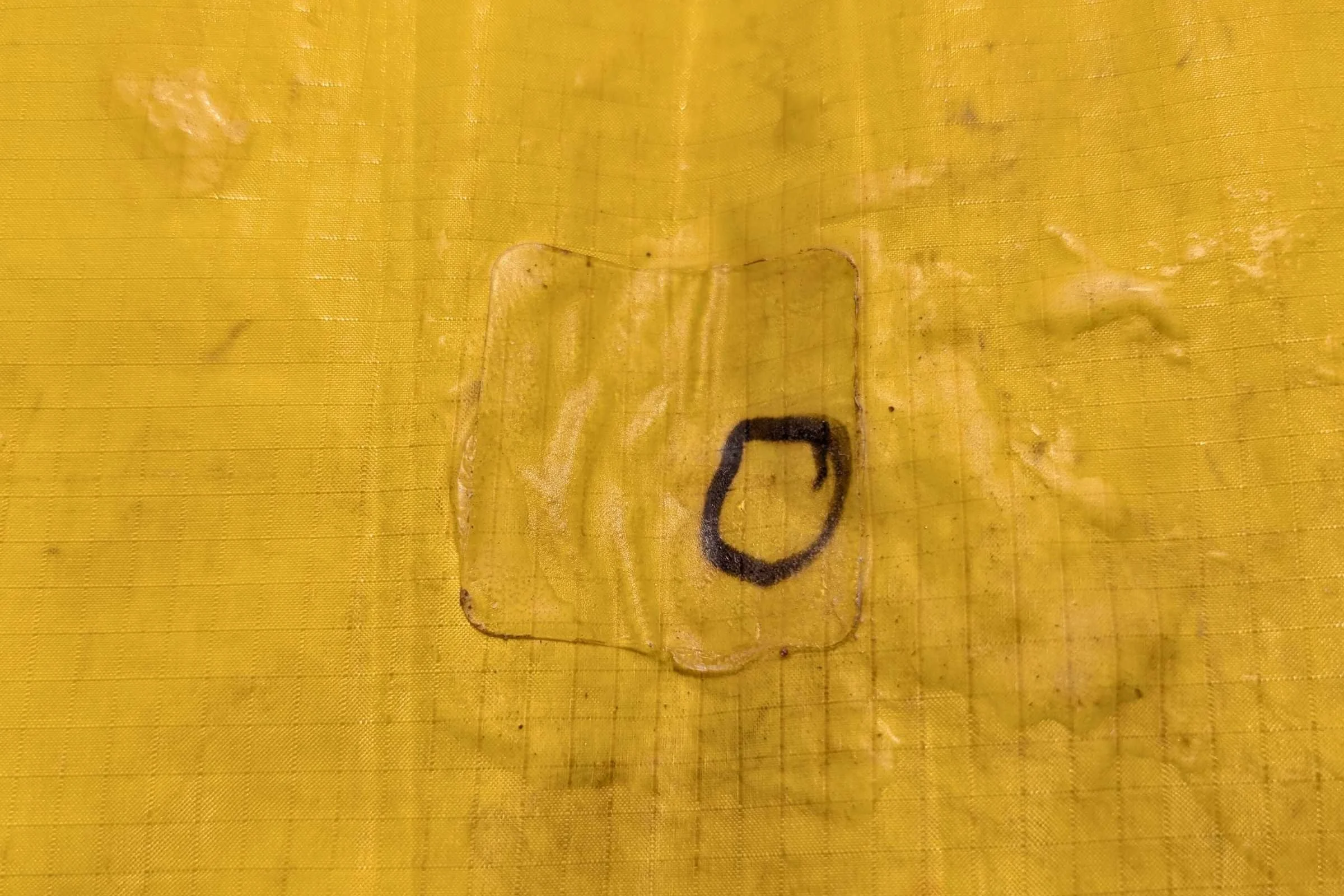 A black Sharpie circle indicating a puncture on the surface of a sleeping pad.