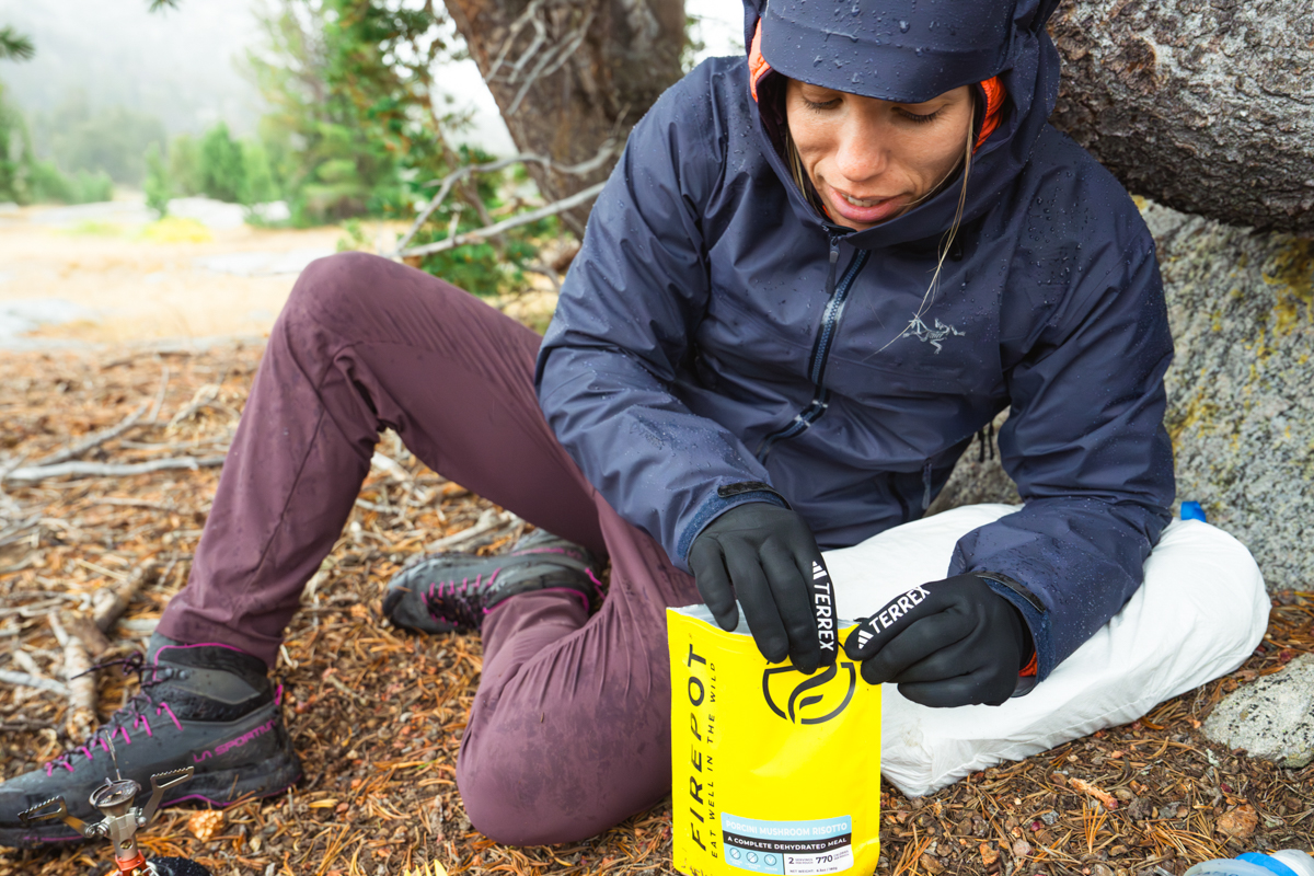 A hiker preparing a Firepot meal which is known for its dietary-friendly options.