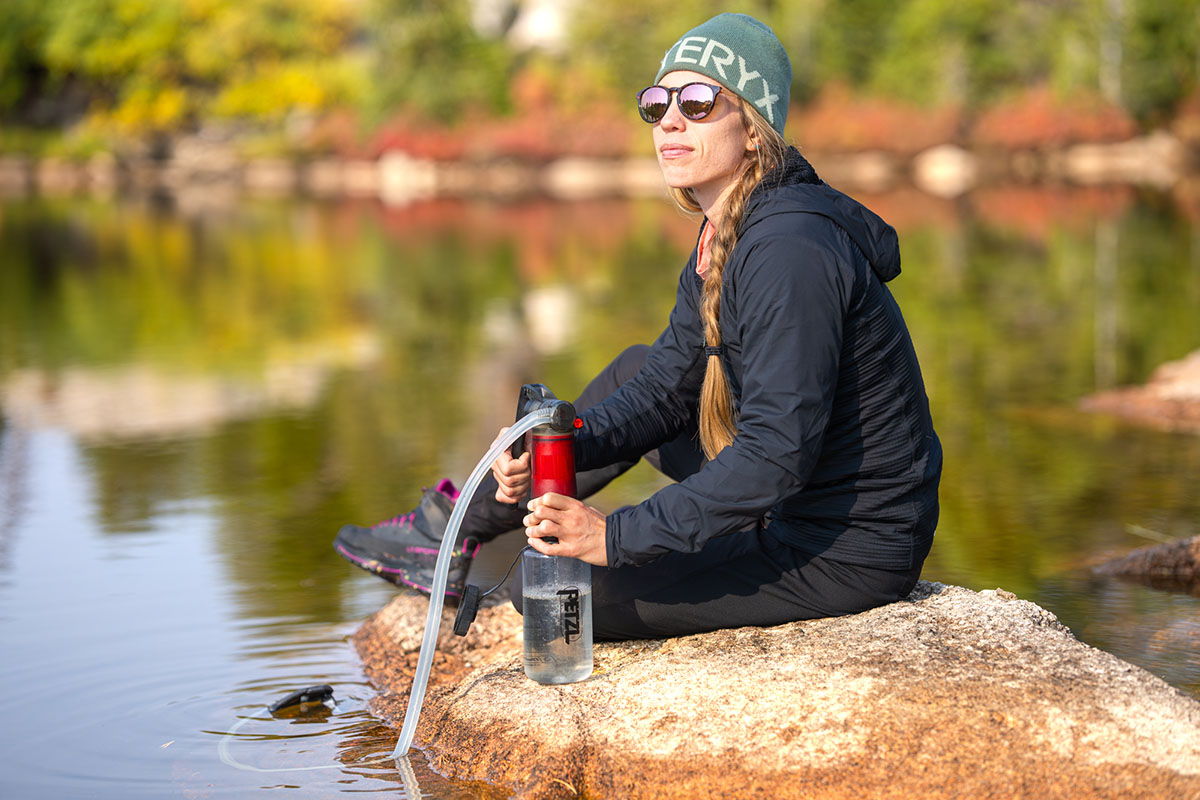 A woman wearing a synthetic jacket while filtering water in the backcountry.