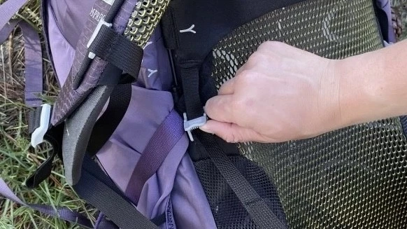 A woman adjusting the sliding torso panel on a technical backpack.