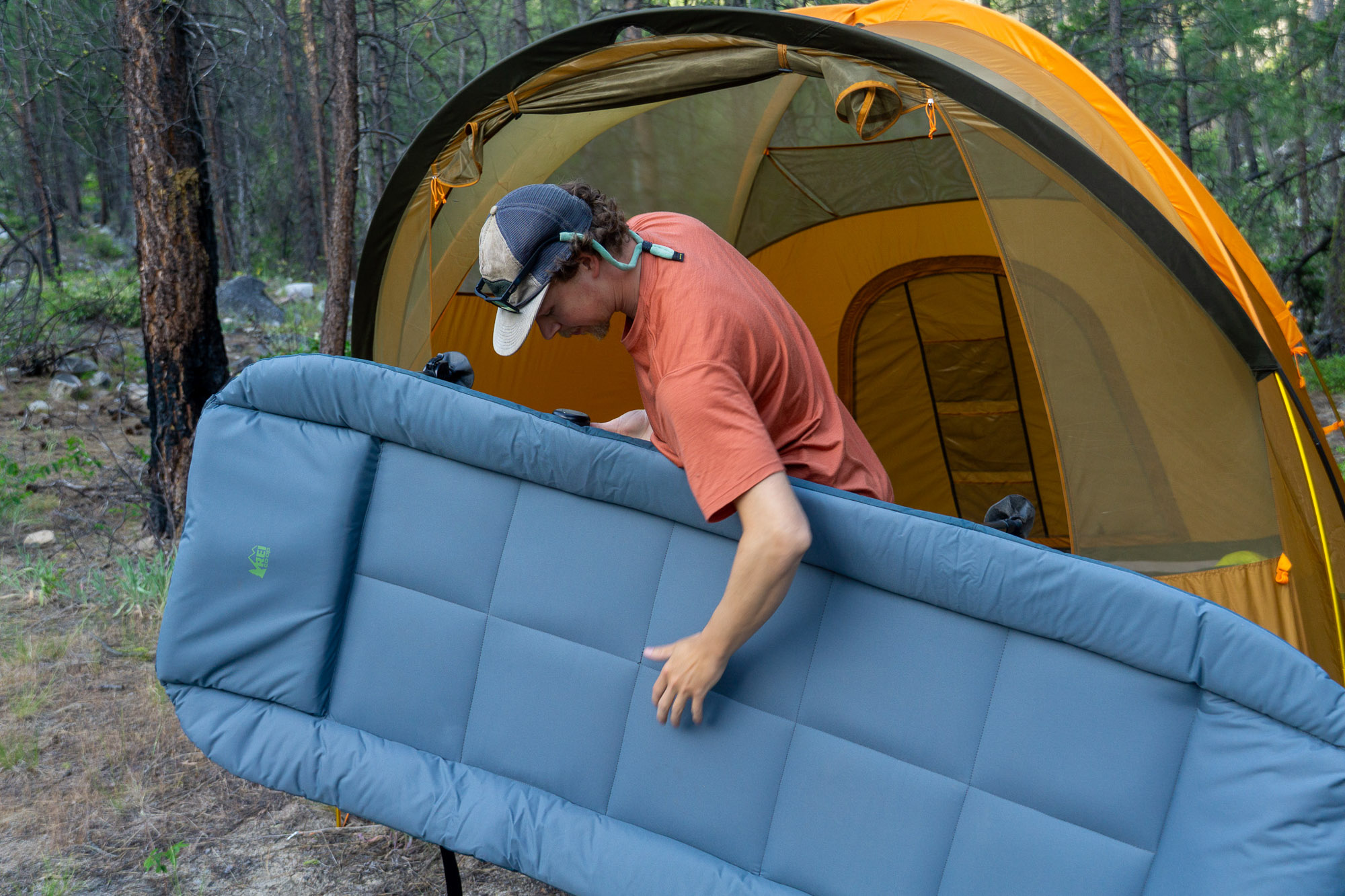 The author carrying the REI Wonderland Comfort Cot towards a tent entrance.