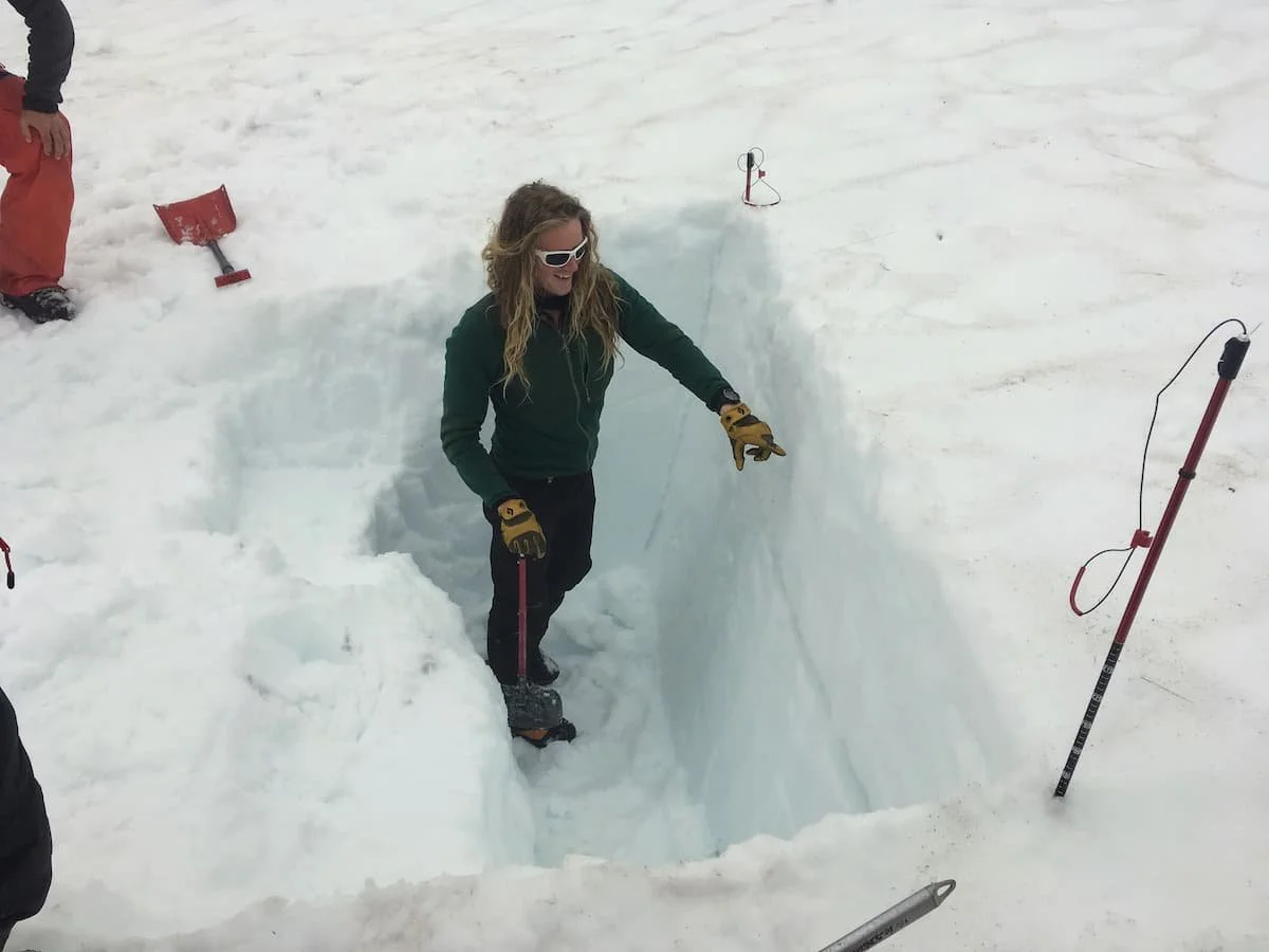 A professional ski guide digging a snow pit to analyze snowpack stability.