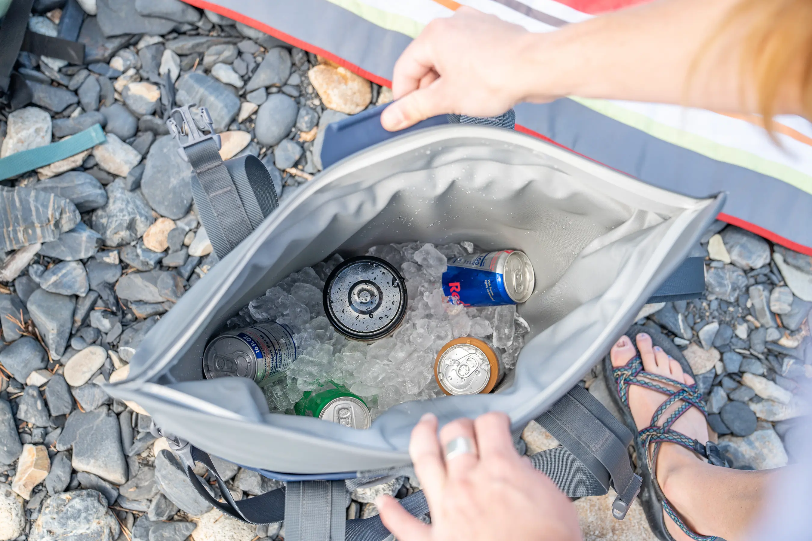Top-down view of an open soft cooler tote showing drinks packed in ice.