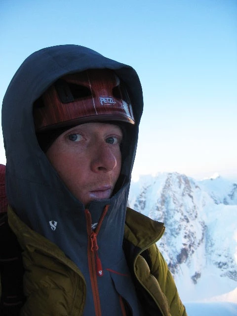 A climber wearing a high-loft down jacket over other layers while stationary.