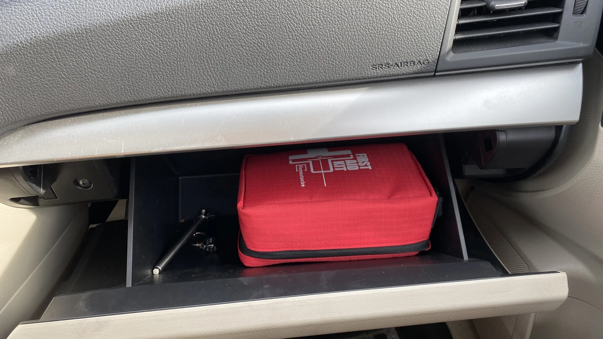 A first aid kit stored in the trunk of a car for roadside emergency readiness.