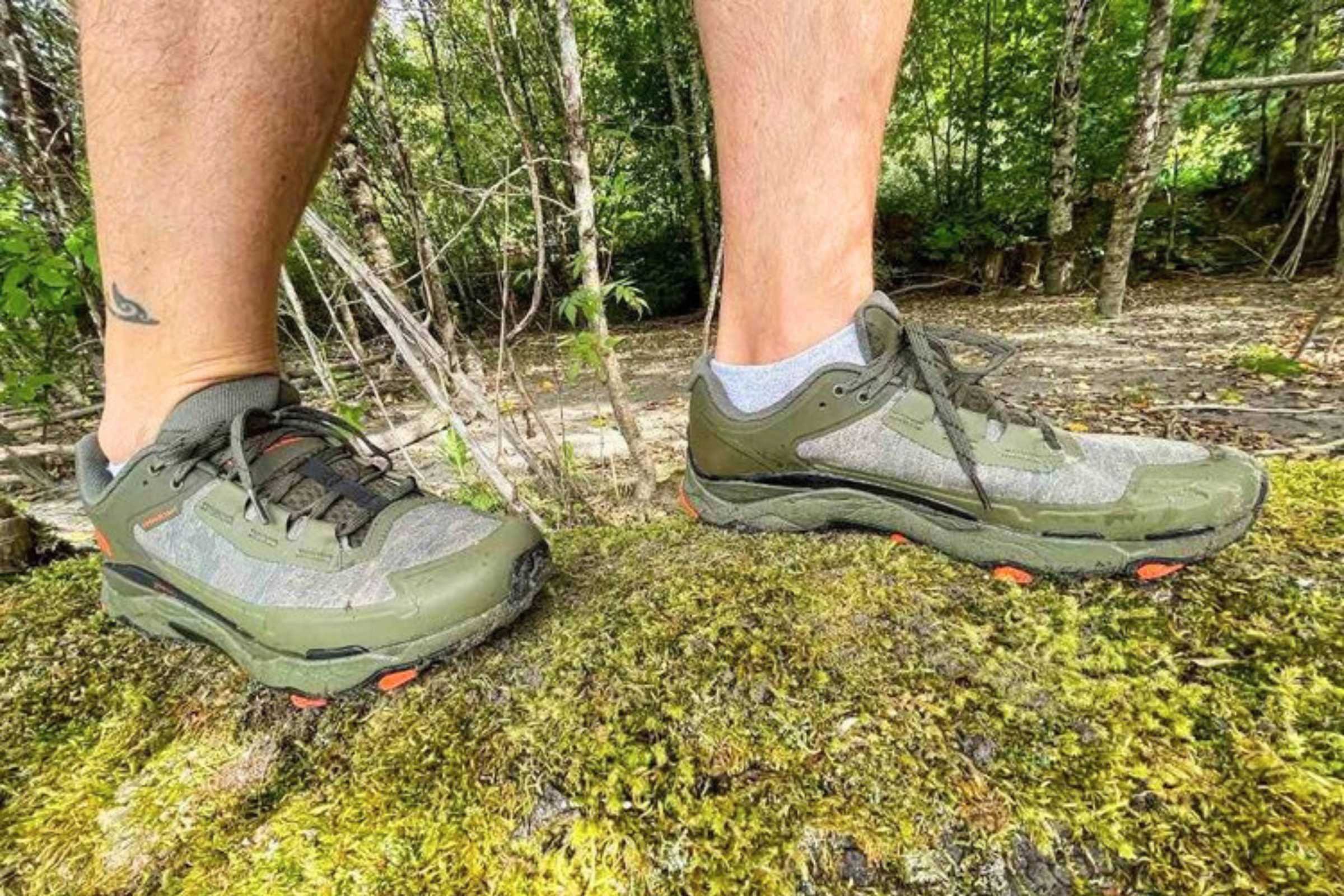 A low-cut hiking shoe and a mid-cut hiking boot placed side-by-side on a trail.