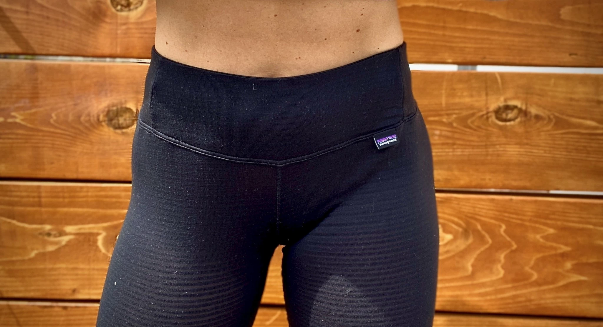 A woman checking the fit of her long underwear in an outdoor setting.