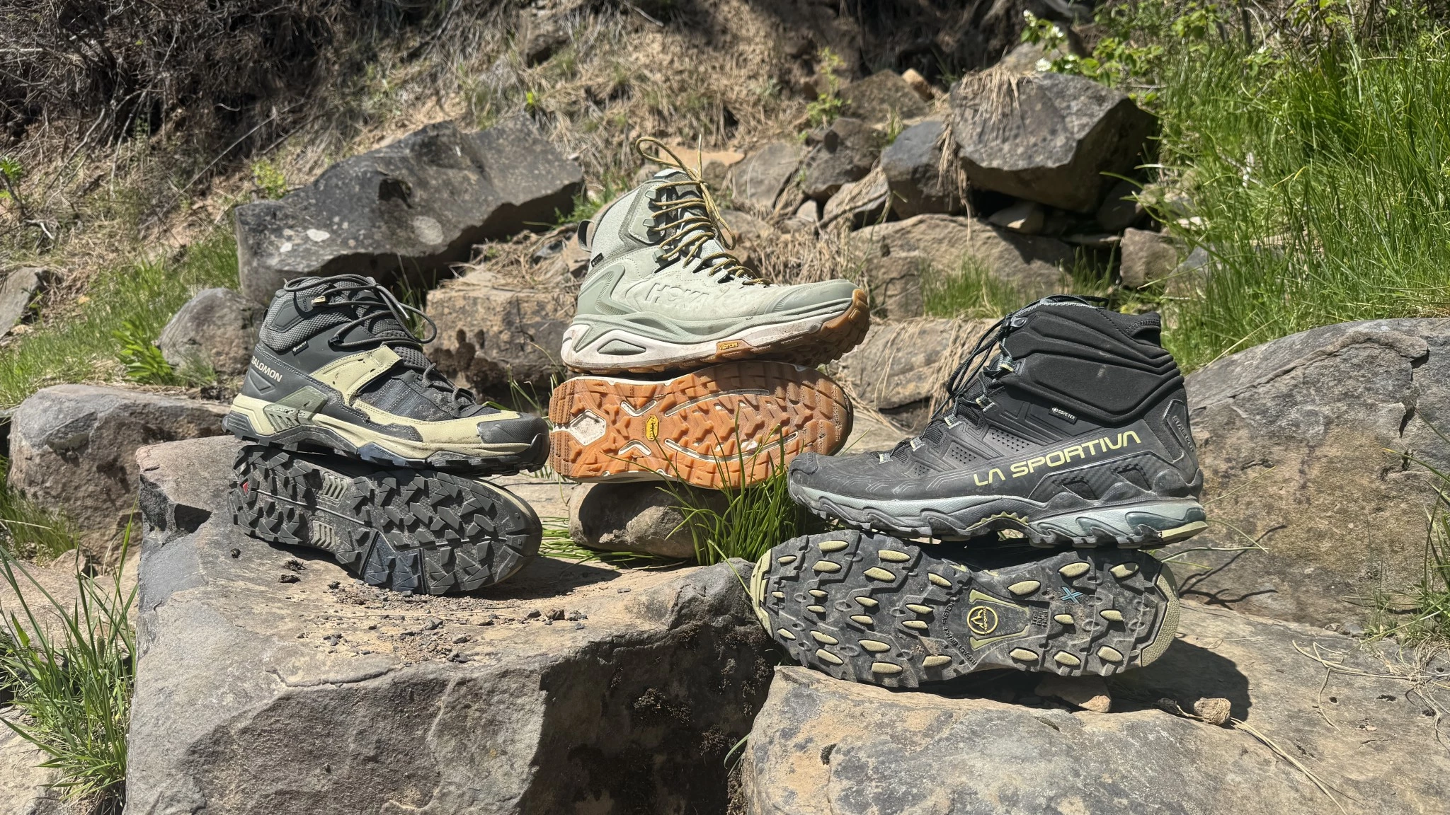 Group of hikers testing various boots side-by-side in a muddy field trail.