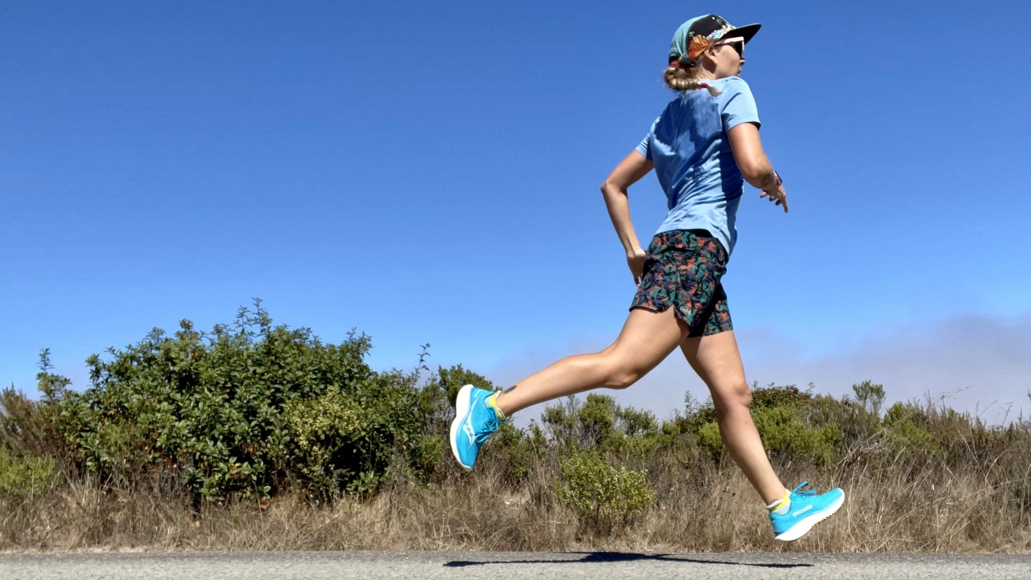 A runner in motion on a sunny trail wearing performance running gear.