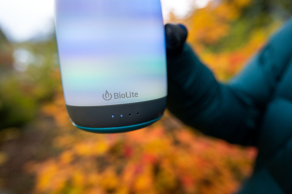 A BioLite AlpenGlow 500 lantern glowing with a warm pink hue on a camping table.
