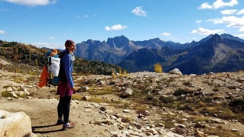 A hiker with a large expedition pack looking out over a mountain vista.