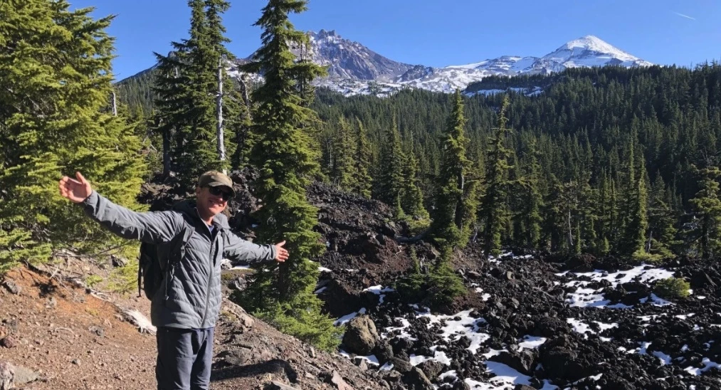 A hiker standing on a scenic trail wearing a well-fitted insulated jacket.