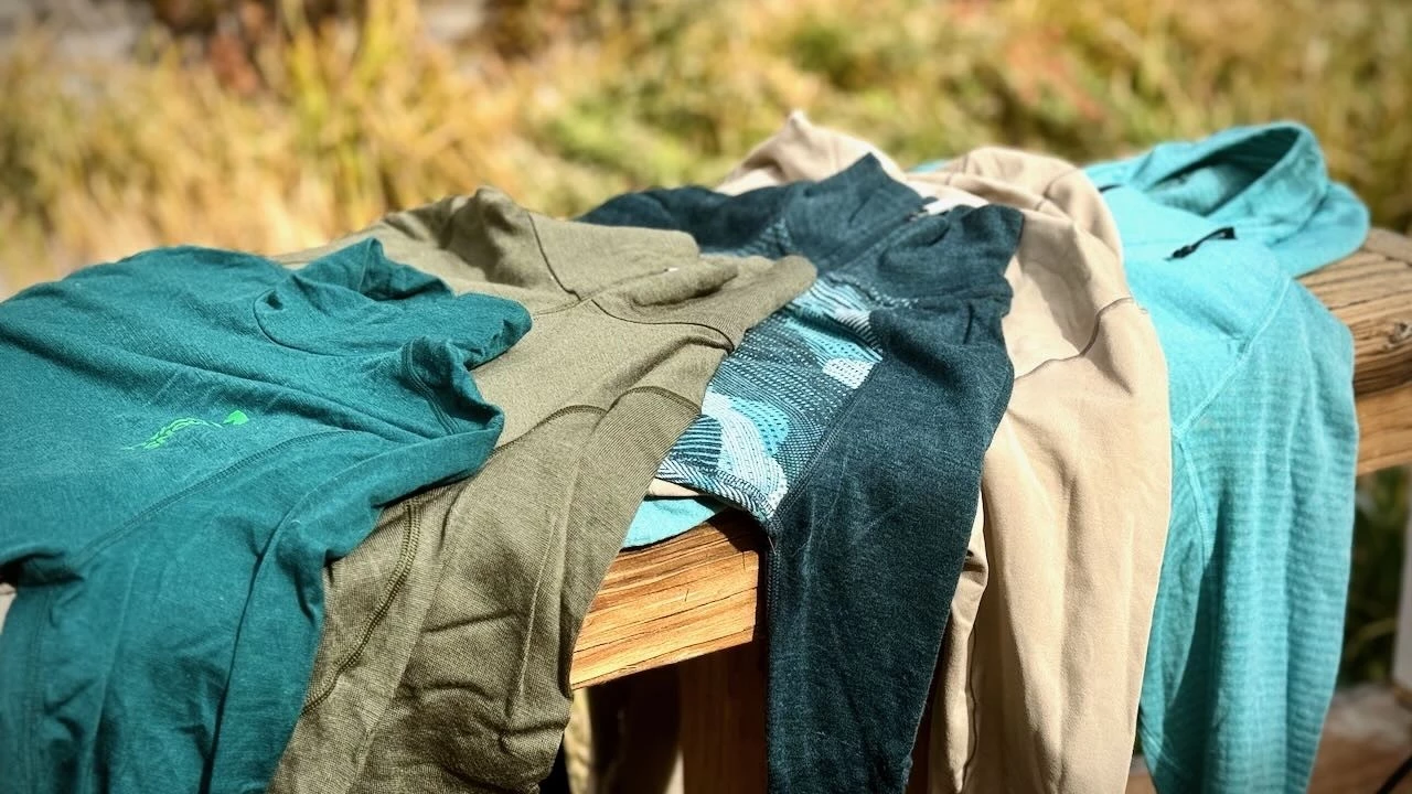 A hand holding different colored base layer fabrics to show varying thicknesses.