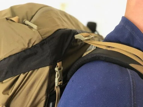 Close-up profile view of a backpack's load lifter strap and its attachment to the shoulder strap.