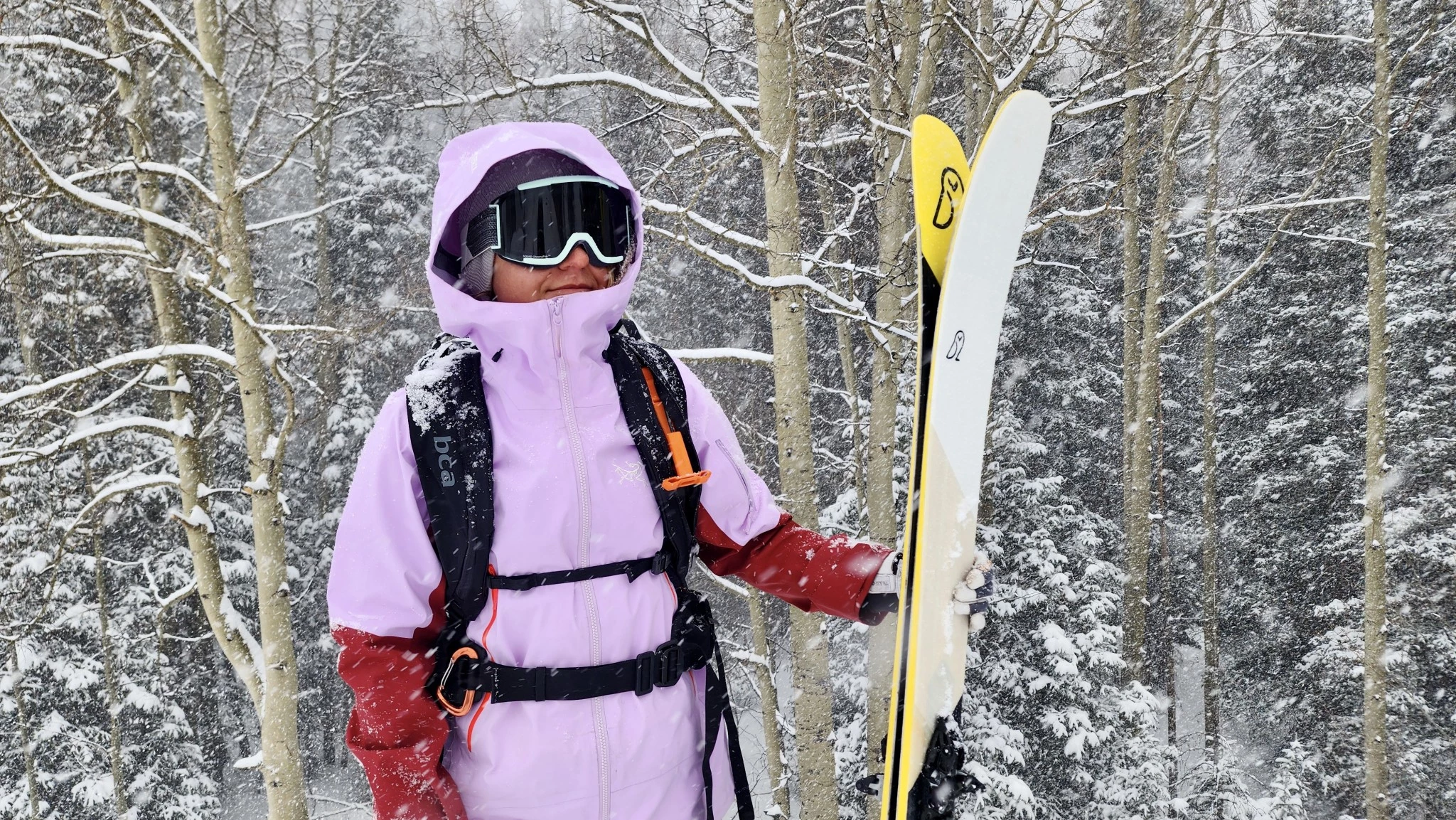 A skier wearing a compact, low-volume avalanche backpack while skiing downhill.