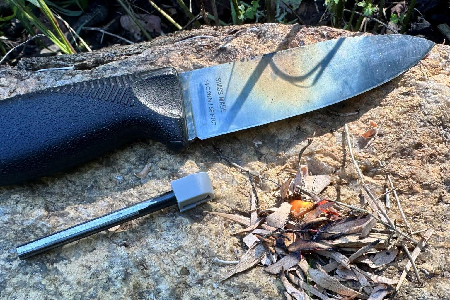 A person using a Victorinox Venture Pro knife to strike a ferro rod and create sparks.