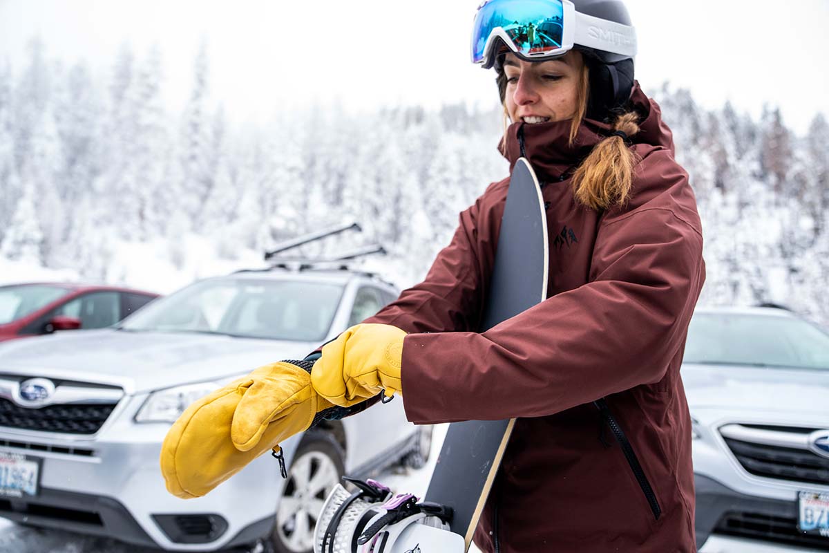 A person pulling on a durable leather snowboard mitten.